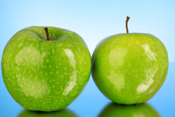 Two green apples on blue background