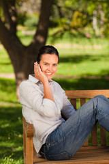 Young beautiful woman phoning on the bench