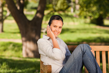 Young beautiful woman phoning on the bench