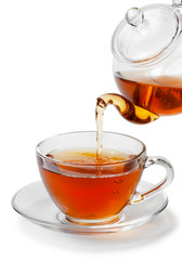 Tea being poured into glass tea cup isolated on a white backgrou