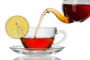 Tea being poured into glass tea cup isolated on a white backgrou
