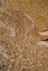 Paddling feet in sand on kephalonia Greece