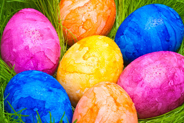 farbige Ostereier mit Tautropfen versteckt im Gras