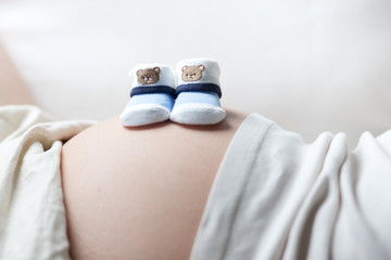 schwangere Frau mit Babyschuhen auf dem Bauch - 30789154