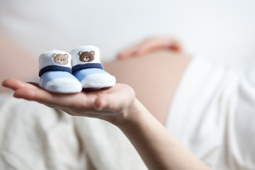 schwangere Frau mit Babyschuhen auf der Hand - 30789164