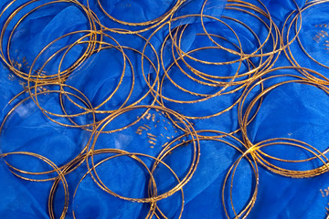 Thin gold bangles scattered on a blue textile