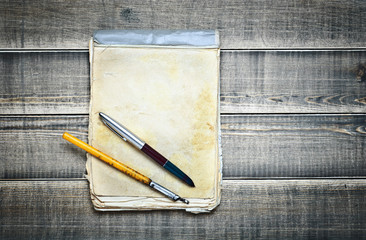 old notebook with pens on a wooden surface