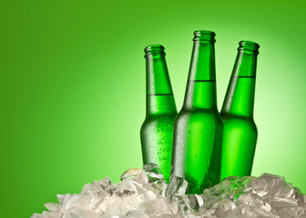 Three beer bottles getting cool in ice cubes
