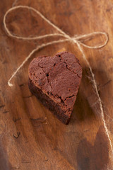 chocolate brownie heart with bow, rough wooden background