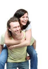 Happy young couple in jeans, funny girl jumps on boyfriend back