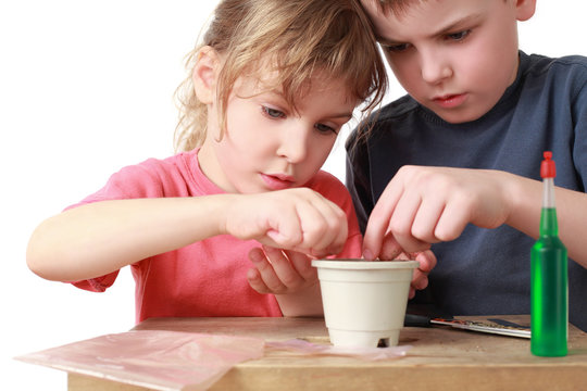 Girl and boy seat grains in  pot
