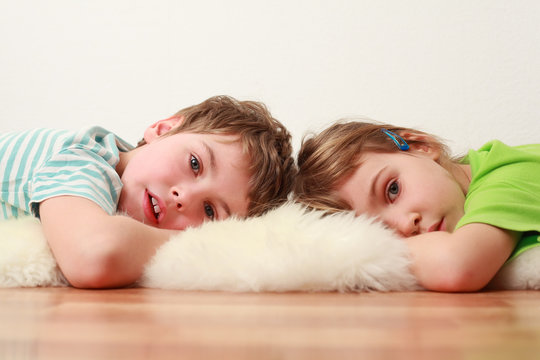 Little Brother And Sister Lying On Floor On White Skin