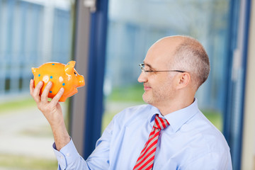 zufriedener geschäftsmann mit sparschwein