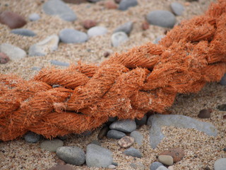 Оранжевый канат лежит на песке