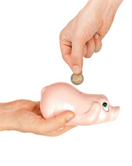 Inserting coin to piggy coin bank over white