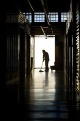 Silhouette of man moping floor