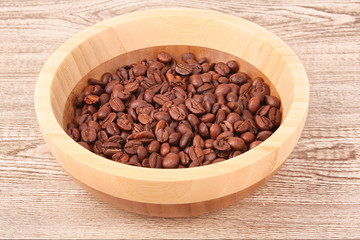 Plate with coffee beans on wooden table