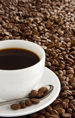 cup of coffee, spoon and on beans