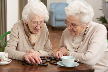 Two Senior Women Playing Dominoes At Day Care Centre