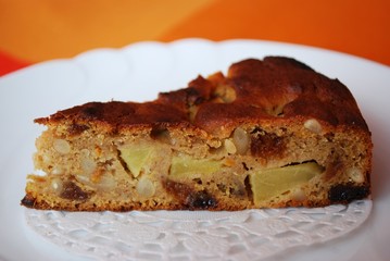Slice of an apple pie on white plate and orange background