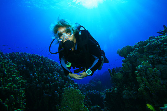 Young Woman Scuba Diving over coral reef