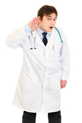 Concentrated medical doctor holding hand at ear and listening