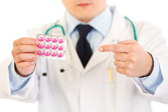 Medical doctor pointing finger on pack of pills. Close-up.