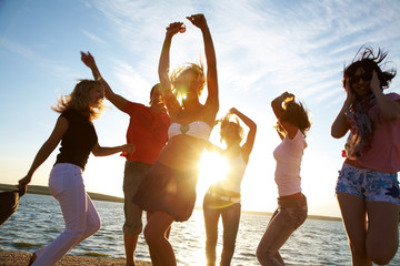 happy young people dancing at the beach