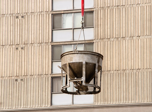 Cement Bucket swinging in front of building