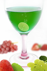 green alcohol cocktail with mix fruit on white background