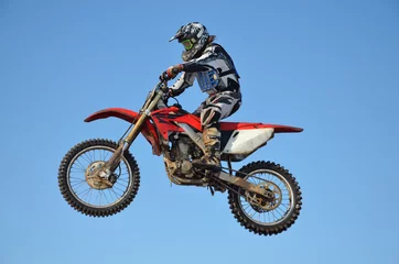 Stof per meter motocross rider flying high in the air against the blue sky © VVKSAM