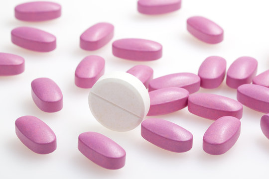 white pill on a background of pink tablets