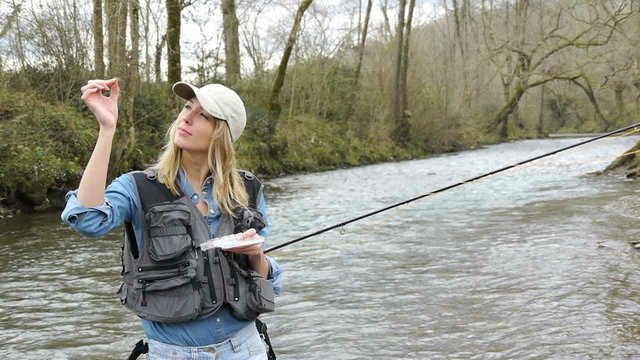 Woman in river using fishing rod