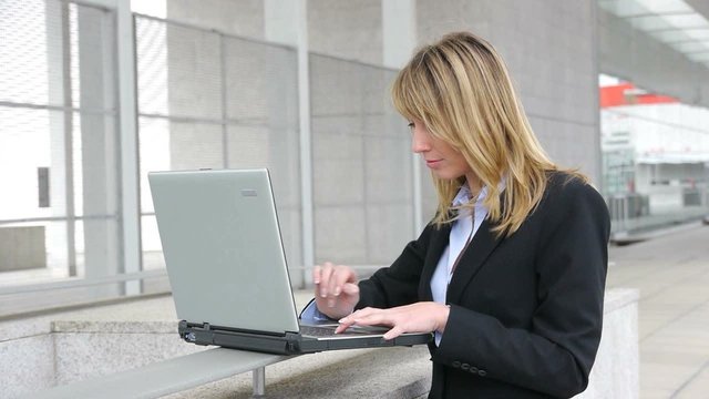 Businesswoman working on laptop computer outside