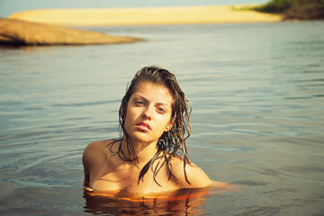 exotic girl with wet hair relaxed in tranquil golden fresh water
