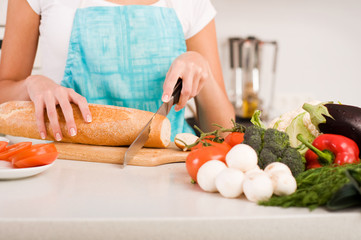 Obraz na płótnie Canvas Woman cutting bread on the kitchen