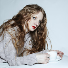 Portrait woman with a cup of coffee lying on a sofa