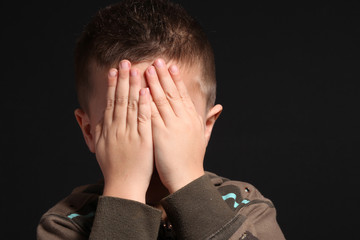 bambino si copre il volto con le mani