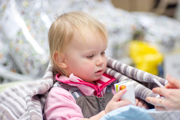 Adorable baby sit in shopping cart with small pack of juice