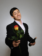 Handsome romantic young man holding rose flower and vine bottle