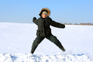 Fototapeta na wymiar happy kid jumping in the winter field