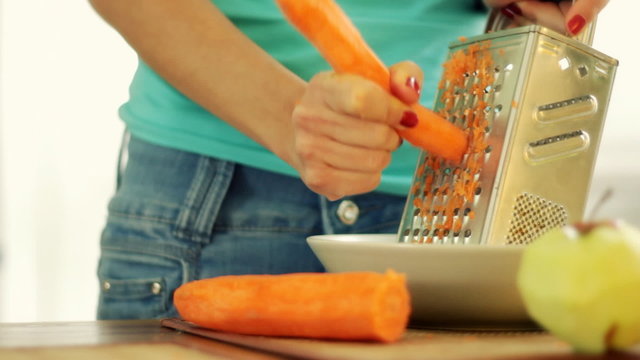 Woman grating carrot on grater and eating carrot, steadicam shot