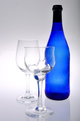 Two wine glasses and blue bottle isolated on white background.