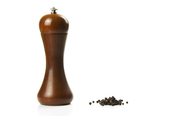 A pepper mill and some black pepper on a white background