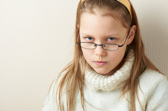 Portrait of a displeased little girl in eyeglasses
