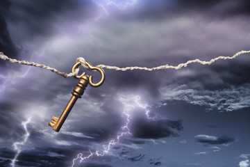 old key attached to a kite flying in a storm