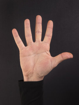 Palma de la mano abierta de un hombre sobre fondo negro aislado y liso. Vista de frente