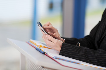 frau im büro tippt auf handy