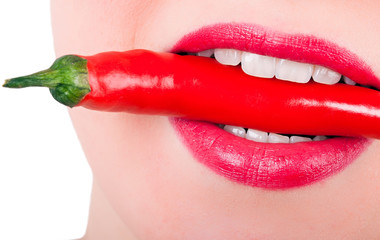 eine rote Peperoni zwischen den Zähnen