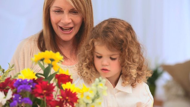 A grandmother with her grand daughter making a bunch of flowers